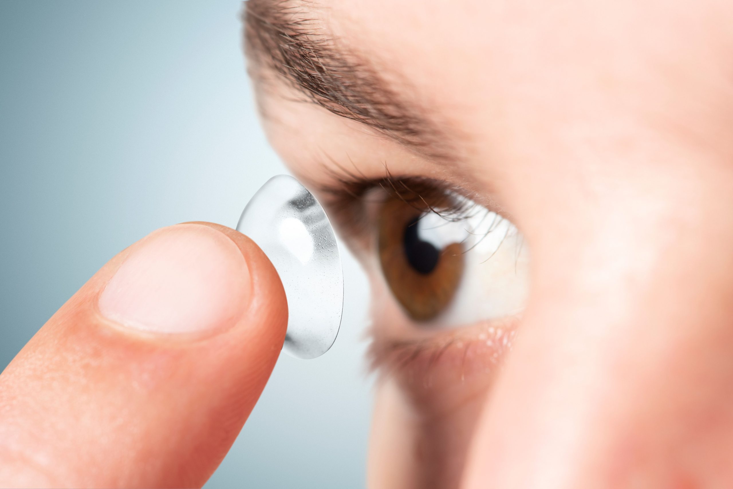 man applying his contact lens scaled